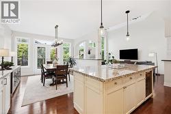Kitchen island with stone countertop, built-in beverage cooler, and pendant lighting - 