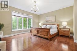 Hardwood flooring, curved bay window, neutral wall tones, elegant chandelier, vaulted ceiling - 