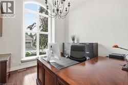 Arched window with sill seating, wood-finish flooring, and a multi-arm chandelier - 
