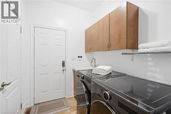 Laundry area featuring a utility sink, wood-finish cabinetry, and a wall-mounted shelving unit - 