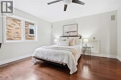 Rich wood-finish flooring, white walls, a ceiling fan, and integrated wall speakers - 
