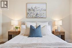 Upholstered headboard with button-tufting, smooth wall finishes, wood-finish flooring, and recessed lighting - 