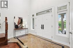 Double entry doors with transom window, sidelight windows, high ceilings, large format tile flooring, and wood-finish stair railing - 