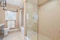 Bathroom featuring a glass-enclosed shower, separate bathtub, and tile flooring - 