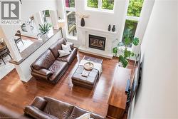 Hardwood flooring throughout, two-story great room with fireplace, white mantel, large windows, and an arched entry - 