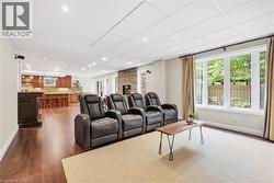 Open-concept lower level with recessed lighting, wood-finish flooring, a built-in wet bar, and a stone-clad fireplace - 