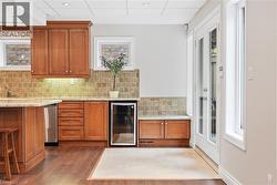 Wood-finish flooring, French doors with full-length glass panels, recessed ceiling lighting, and a tiled backsplash - 