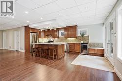 Wood-finish flooring throughout, kitchen with wood cabinetry, stainless steel appliances, and a central island - 