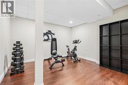 Finished basement room featuring wood-finish flooring, drop ceiling, and extensive built-in shelving - 
