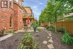 Exterior brick facade with a concrete patio, wood fence, mature trees, and a stone-stepped pathway - 