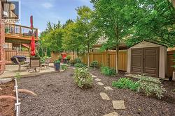 Expansive backyard featuring a concrete patio, wood privacy fence, mature trees, and a garden shed - 