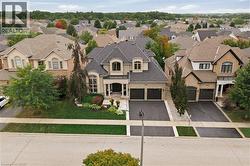 Stately residence featuring a dark gray shingle roof, light-toned facade, multiple dormer windows, and an arched entry portico - 