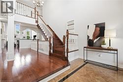 Two-story foyer with a chandelier, wood-finish flooring, and a grand staircase featuring wood handrails and white balusters - 