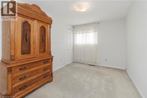 Neutral wall paint with carpet flooring, a window with sheer curtains, and a ceiling-mounted light fixture - 36 Buckingham Drive, Hamilton, ON 