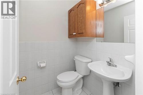 White pedestal sink with chrome faucet, wall-mounted mirror, and wood-finish cabinetry - 36 Buckingham Drive, Hamilton, ON 
