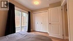 Sliding glass door leading to outdoor space, wood-finish flooring, paneled closet doors, paneled interior door, and ceiling-mounted light fixture - 