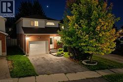 Brick and siding exterior with an integrated garage, paved driveway, and established front landscaping - 