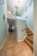 Two-story entry with tile flooring, wood-finish stairs, and an upper-level railing - 