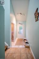 Tile flooring, track lighting, and a white entry door with decorative glass inserts - 