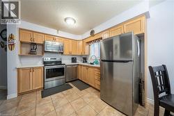 Kitchen featuring wood-finish cabinetry, stainless steel appliances, light-toned countertops, and tiled flooring - 