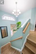 Staircase featuring wood-finish treads and risers, light wood handrails, and a decorative transom window - 