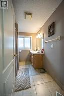 Tiled flooring, wood-finish vanity with a built-in sink, wall-mounted light fixture, and a window - 