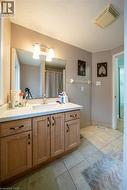Vanity with integrated sink, wood-finish cabinetry, and surface-mounted lighting - 
