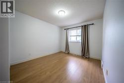 Wood-finish flooring, white walls, and a window with blinds - 