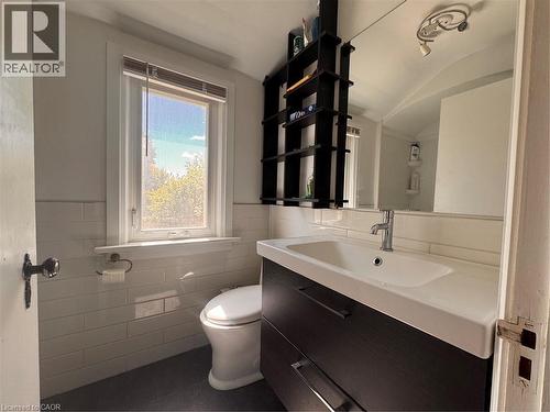 White subway tile wainscoting, a single vanity with integrated sink, and a wall-mounted mirror - 225 Bridgeport Road E, Waterloo, ON 