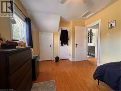Hardwood flooring throughout, multiple built-in closets, window with blinds, and ceiling-mounted light fixture - 