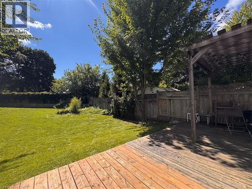 Expansive outdoor area featuring a wood deck, wood pergola, and a spacious lawn bordered by a wood fence - 225 Bridgeport Road E, Waterloo, ON 