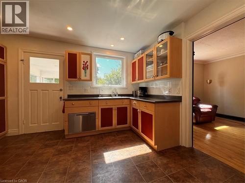 Kitchen featuring tile flooring, recessed lighting, wood-finish cabinetry with red paneling, and a stainless steel dishwasher - 225 Bridgeport Road E, Waterloo, ON 