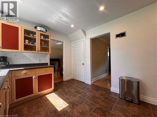 Kitchen featuring wood cabinetry with red paneling, glass-front upper cabinets, and dark countertops - 225 Bridgeport Road E, Waterloo, ON 