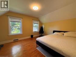 Hardwood flooring, two double-hung windows, sloped ceiling, and a flush-mount ceiling light fixture - 