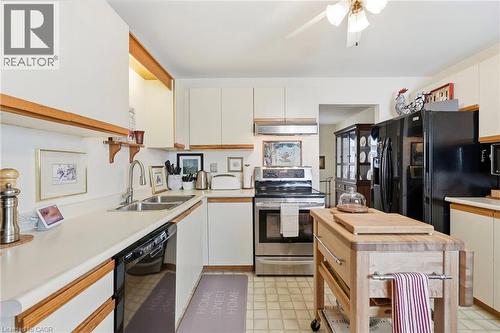Kitchen featuring white cabinetry, light countertops, a stainless steel range, and a black refrigerator - 89 Brigade Drive, Hamilton, ON 