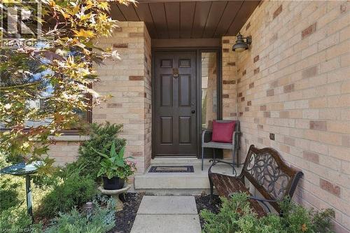 Brick exterior with a paneled entry door, transom window, and an overhead outdoor light fixture - 89 Brigade Drive, Hamilton, ON 