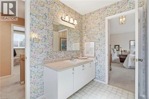 Vanity with integrated sink, overhead wall-mounted light fixture, mirror, and storage cabinetry - 89 Brigade Drive, Hamilton, ON 
