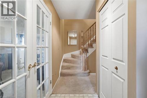 French doors with brass hardware, carpeted staircase with wood banister, and a paneled closet door - 89 Brigade Drive, Hamilton, ON 