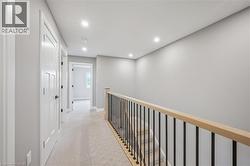 Carpeted hallway with recessed lighting, light gray walls, and white trim - 