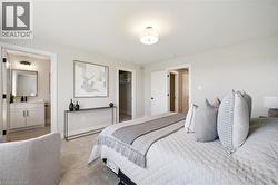 Wall-to-wall carpeting, overhead ceiling light fixture, white interior doors, and a bathroom featuring a vanity with a rectangular mirror and wall-mounted lighting - 