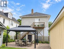 Paver patio with a metal-roof gazebo, elevated wood deck with railing, and a storage shed - 