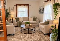 White walls with wood-trimmed windows, a light-colored sofa, and matching armchairs - 
