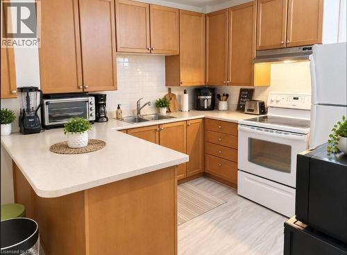 Light wood-finish cabinetry, white subway tile backsplash, white countertops, built-in stainless steel sink, and light wood-finish flooring - 60 Lynnwood Avenue, Simcoe, ON 