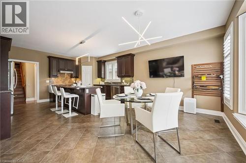 Dark wood cabinetry, stainless steel appliances, tile flooring, modern light fixtures, and window shutters - 517 Topper Woods Crescent, Kitchener, ON 
