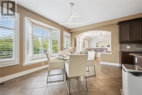Bay window with plantation shutters, tile flooring, contemporary chandelier, arched entryway, and dark wood cabinetry with tiled backsplash - 517 Topper Woods Crescent, Kitchener, ON 