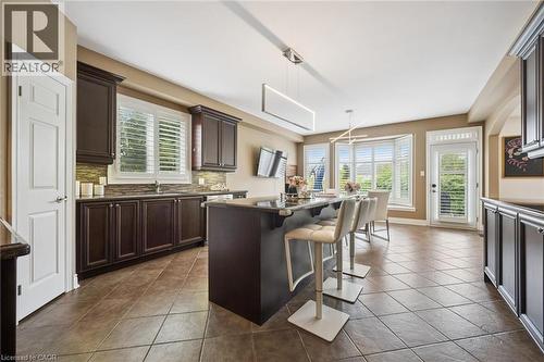 Dark wood cabinetry, a center island, and a tile backsplash - 517 Topper Woods Crescent, Kitchener, ON 