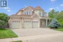 Brick and stone exterior with a turret feature, three-car garage, covered entry porch, and mature landscaping - 517 Topper Woods Crescent, Kitchener, ON 