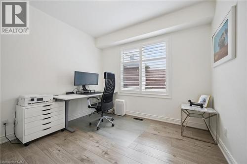 Bright room with wood-finish flooring, white walls, and a window featuring white plantation shutters - 517 Topper Woods Crescent, Kitchener, ON 