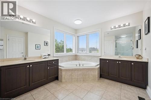 Dual vanities with integrated sinks, a corner jetted tub, large windows, and tiled flooring - 517 Topper Woods Crescent, Kitchener, ON 