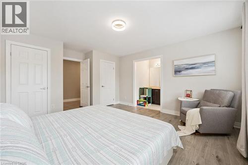 Spacious room featuring wood-finish flooring, light gray walls, and a contemporary ceiling light fixture - 517 Topper Woods Crescent, Kitchener, ON 
